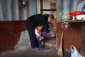 Woman helping her child put her shoes on